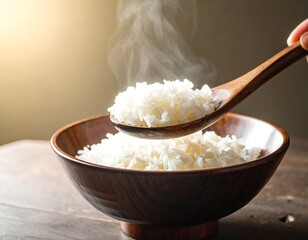Steaming white cooked rice served in a dark wooden bowl with a hand holding a wooden spoon