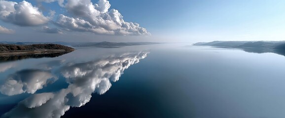 Fototapeta premium Serene lake reflecting a sky of fluffy clouds