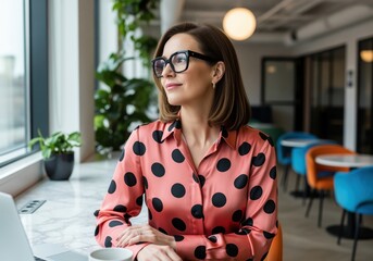 Thoughtful mature woman in stylish polka dot blouse and black framed glasses