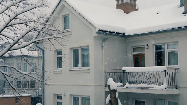 peaceful and calm city scene in the coldest season where frozen precipitation builds up on the sides and railings of an apartment block  together with leafless arbor limbs generating a quiet and