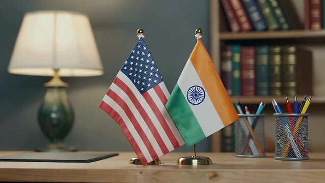 horizontally oriented photographic arrangement depicting the paired national standards of two nations resting on a work surface against an out-of-focus backdrop  emphasizing selective sharpness and