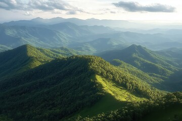 Expansive view of rolling green mountains covered with dense forest under a partly cloudy sky with soft sunlight illuminating the landscape