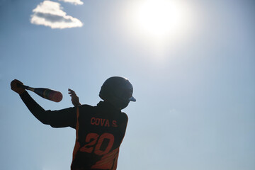 Youth baseball player swinging during game or practice under blue sky