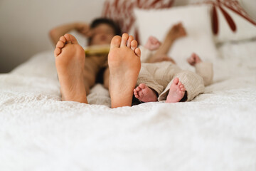 Two pairs of feet two little boys brothers rest on a soft, white bedspread, symbolizing connection...