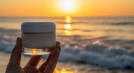 Hand Holding Cosmetic Jar at Sunset Beach Scene with Warm Colors and Calm Ocean