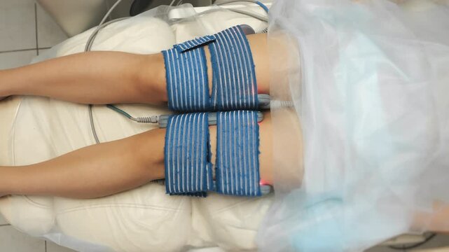 Professional myostimulation treatment on legs in modern beauty clinic. Electrotherapy session for body toning and cellulite reduction indoors.
