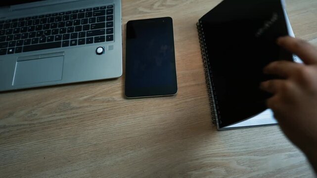Workspace with a laptop, smartphone, and notebook on a wooden desk