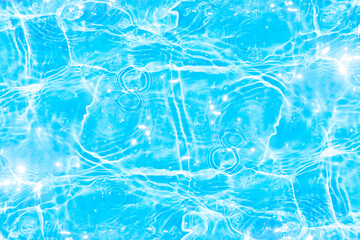 Blue water with ripples on the surface. Defocus blurred transparent blue colored clear calm water surface texture with splashes and bubbles. Water waves with shining pattern texture background.