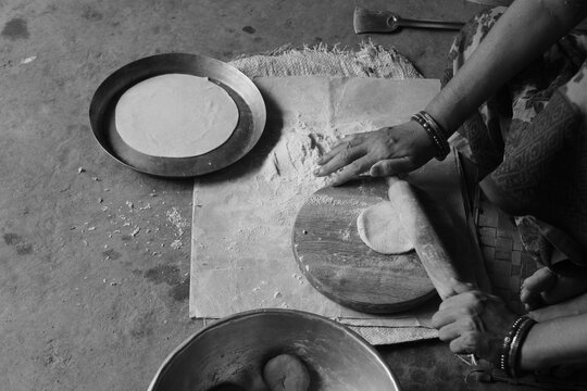 Indian Woman Rolling Roti or Chapati Dough with Wooden Rolling Pin on Chakla, Traditional Indian Cooking, Homemade Flatbread Preparation and Food Culture