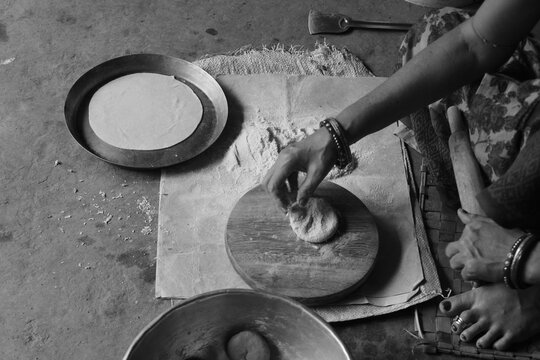 Indian Woman Rolling Roti or Chapati Dough with Wooden Rolling Pin on Chakla, Traditional Indian Cooking, Homemade Flatbread Preparation and Food Culture