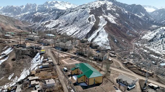 Aerial view of the remote former Soviet uranium and coal mining village with old wooden houses and unpaved roads nestled in a mountain valley
