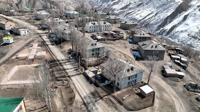 Aerial view of the remote former Soviet uranium and coal mining village with old wooden houses and unpaved roads nestled in a mountain valley