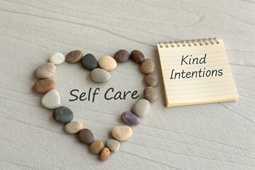 Heart Shape of Pebbles Representing Self Care Next to Notepad