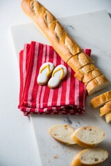 A baguette bread next to a striped red and white towel with yellow flip-flops a picnic or french summer concept