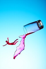 A dramatic high-speed shot of red liquid splashing out of an overturned glass against a bright blue background