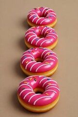 A close-up diagonal view of pink glazed donuts with sprinkles lined up against a plain brown background