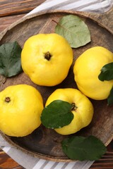 Fresh ripe quinces with leaves on wooden table, top view