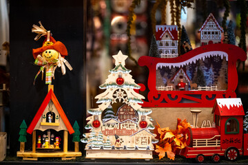 Colorful handcrafted wooden holiday decorations including a Christmas tree, sleigh, train, and small figurines on display at a festive market.