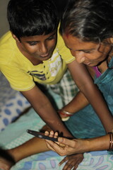 Obraz premium Happy senior woman in colorful saree holding a smartphone and video chatting, representing love, family bonds, and the beauty of technology connecting generations.