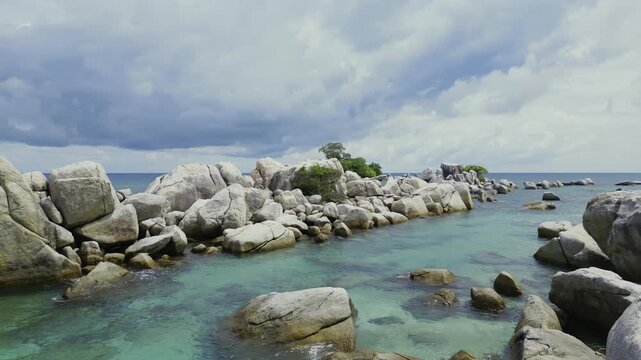 Fly through huge granite rocks meet the stunning clear turquoise water on a cloudy day