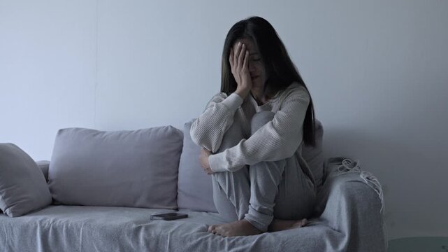 Young Asian woman sitting  on the sofa at home, feeling sad tired and worried suffering depression in mental health. in concept of depression anxiety and insomnia