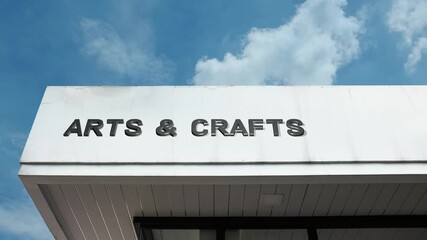 Arts and Crafts word sign displayed on the exterior of a modern building under a clear blue sky, symbolizing creativity, handmade work, artistic expression, design, and cultural craftsmanship