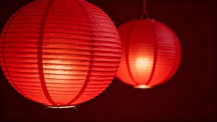 Obraz premium Two glowing red paper lanterns illuminated against a dark background, showcasing intricate texture and warm ambiance.