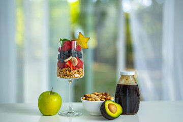 Fresh fruit assortment served in a glass bowl for breakfast. Granola and muesli blend with fruit berries. Healthy food breakfast with natural oatmeal and fruit.