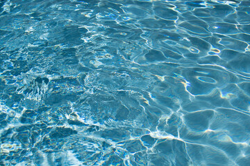 Blue pool water background. Blurred transparent clear calm water surface texture. Water waves in sunlight with copy space.