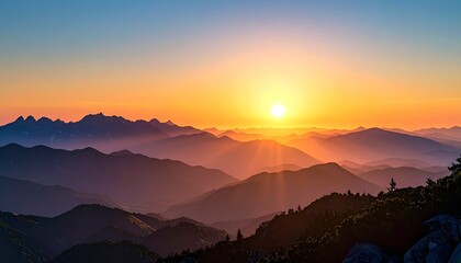 Golden sun rises over layered mountain ranges, casting warm hues and tranquil depth across the horizon.