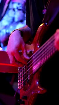 Nighttime bass glow, Close view of bass frets under stage lights, Night scene showcasing glowing bass strings and focused finger techniques under ambient lighting