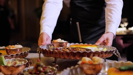 Cinematic slow motion capturing refined banquet service details, Staff meticulously organize sophisticated array of desserts and fruits in stylish hotel dining room