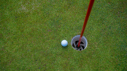 Golf ball is on a green lawn in a beautiful golf course with morning sunshine.