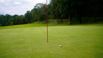 Obraz premium Golf ball is on a green lawn in a beautiful golf course with morning sunshine.