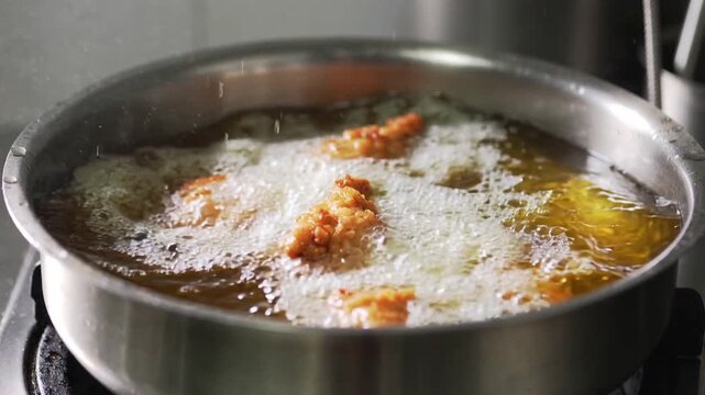 Shiokoji fried chicken karaage drops into bubbling hot oil, creating golden splashes and enzyme-rich foam, captured mid-fry in cinematic slow-motion kitchen lighting.