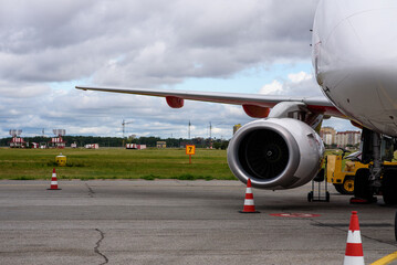 A large passenger airplane is parked at an airport gate with its boarding ramp extended and a clear...