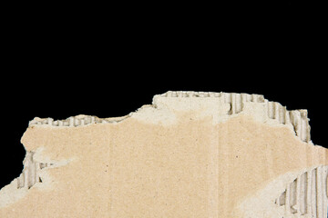 Torn piece of brown cardboard isolated on black background. for industrial, and abstract design.Close-up of ripped cardboard with visible corrugated layers. texture, background.