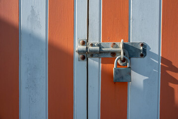 padlocked wooden door with white and red stripes