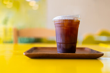 A glass of ice americano coffee placed on wood tray at cafe