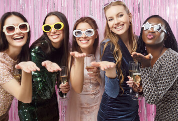 Women friends party, girls smiling and laughing, wearing funny sunglasses and holding champagne blowing kisses, happy birthday party celebration of fun and friendship, bachelorette party happiness 