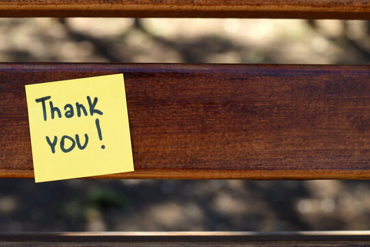 Closeup of Thank You Note with Blurred Background. Macro shot of a yellow sticky note with the words “Thank You!” placed on a wooden surface, with soft bokeh in the background. 