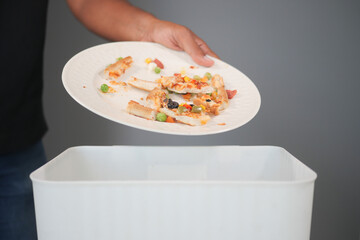 Person discarding leftover food in a waste bin