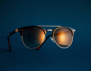 Stylish Clubmaster Sunglasses Mockup with Golden Frame and Warm Reflection on Dark Blue Background