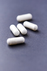 HMB capsules on dark background. Soft focus. Close up. Copy space.	