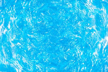 Blue water with ripples on the surface. Defocus blurred transparent blue colored clear calm water surface texture with splashes and bubbles. Water waves with shining pattern texture background.