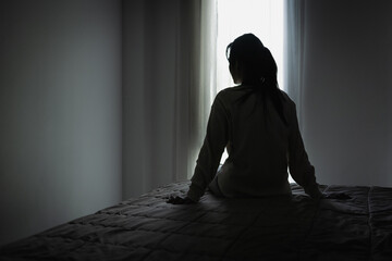 Silhouette of a woman in the bedroom, feeling sad tired and worried suffering depression in mental health. in concept of depression anxiety and insomnia