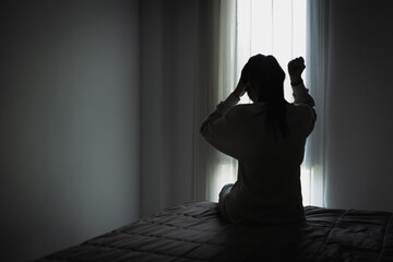 Silhouette of a woman in the bedroom, feeling sad tired and worried suffering depression in mental health. in concept of depression anxiety and insomnia