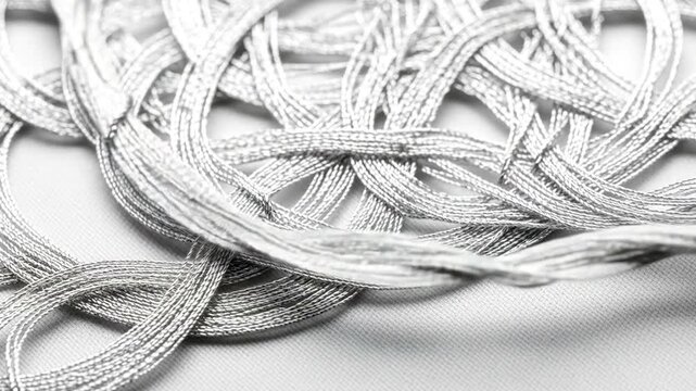 Close-up of intricate silver threads tangled on a white fabric background