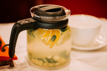 Refreshing lemon and mint beverage served in a clear glass pitcher on a dining table