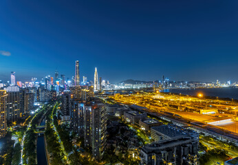 Obraz premium Shenzhen city skyline and waterfront reflecting the vibrant lights during the blue hour after sunset.